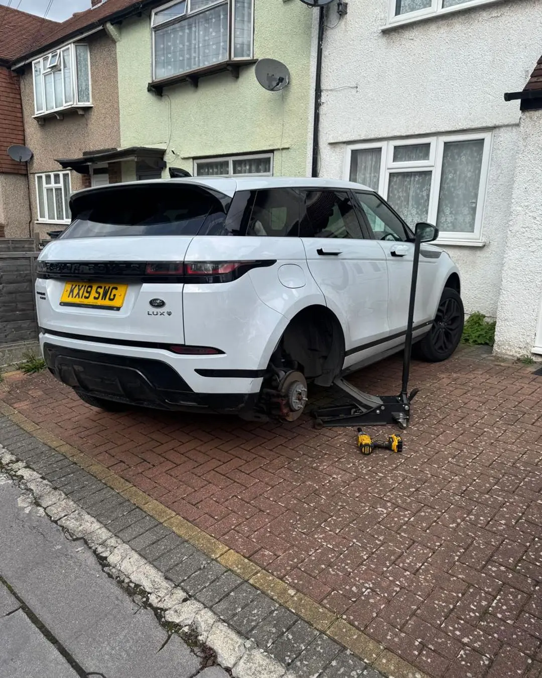 White Range Rover Evoque raised on a trolley jack on a home driveway during a mobile tyre fitting