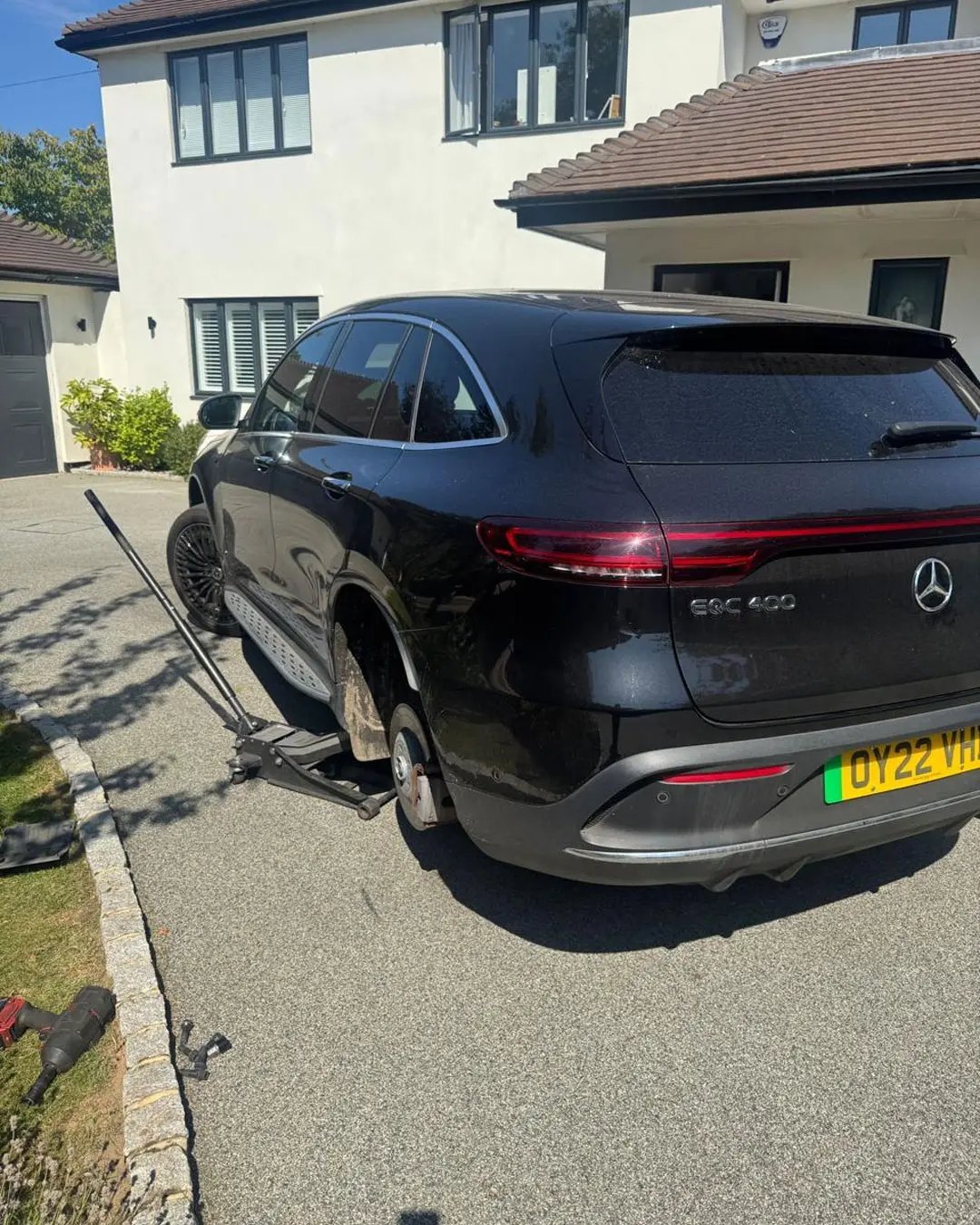 Black Mercedes EQC electric SUV raised on a jack on a driveway