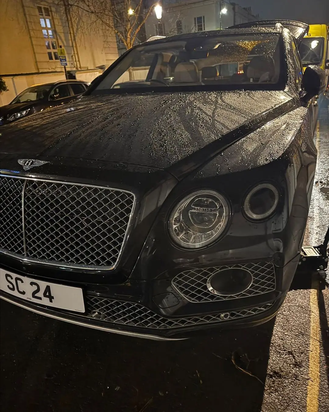 Black Bentley Bentayga with its front wheel off during a night-time call-out